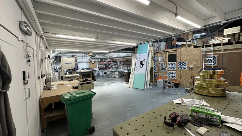 The machine shop: benches, bandsaw, panel saw and racking under strip lights